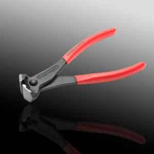 Red-handled diagonal cutting pliers on reflective surface.